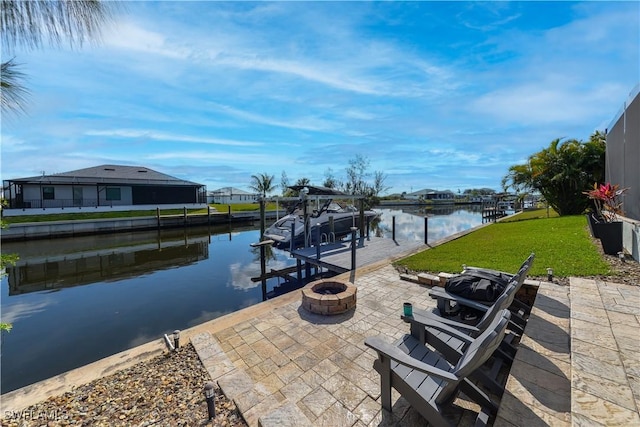 view of dock with a yard, a fire pit, a patio, and a water view