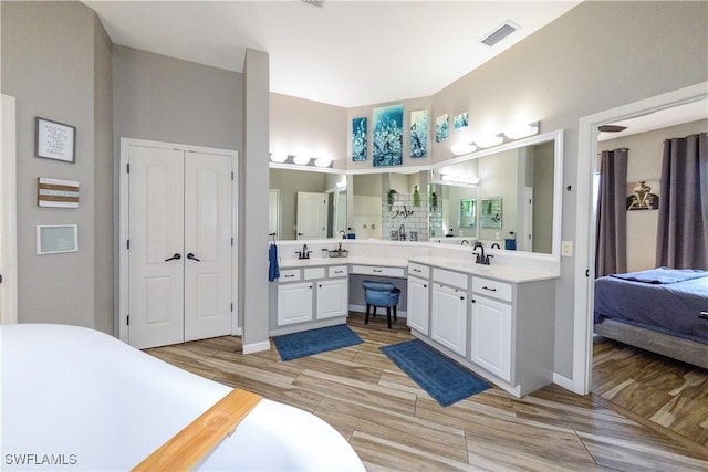 bathroom with wood-type flooring, a washtub, and vanity