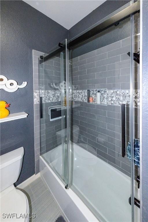 bathroom featuring tile patterned flooring, shower / bath combination with glass door, and toilet