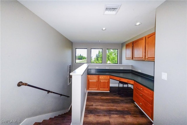 unfurnished office featuring dark hardwood / wood-style flooring and built in desk