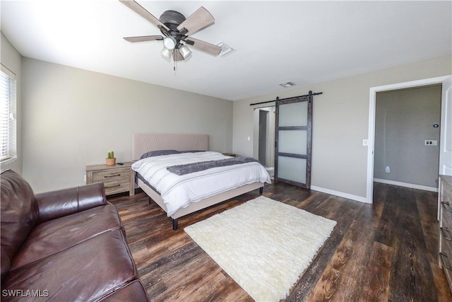 bedroom with ceiling fan, a barn door, and dark hardwood / wood-style flooring