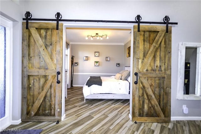 bedroom with hardwood / wood-style flooring, ornamental molding, and a barn door