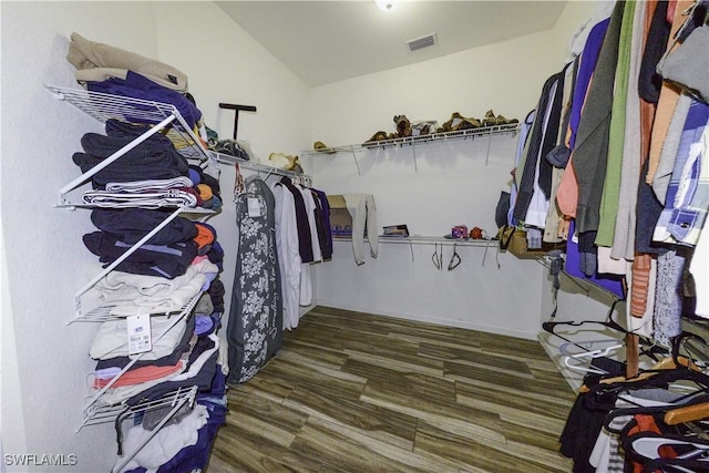 spacious closet with lofted ceiling and dark hardwood / wood-style flooring