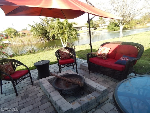 view of patio featuring an outdoor fire pit, a water view, and a fenced backyard