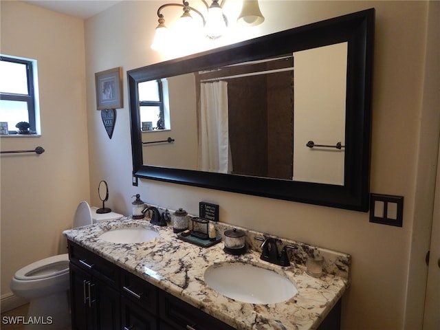 bathroom featuring a sink, toilet, and double vanity