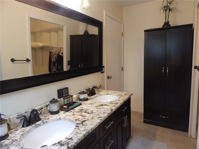 full bath featuring double vanity, a walk in closet, and a sink