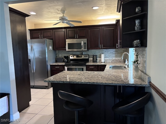 kitchen featuring a peninsula, a breakfast bar, stainless steel appliances, and a sink