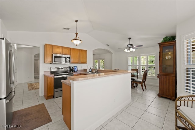 kitchen with pendant lighting, light tile patterned floors, stainless steel appliances, and lofted ceiling