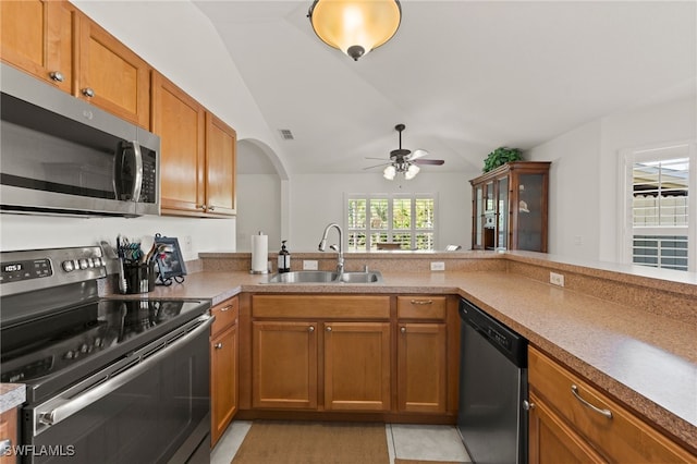 kitchen with appliances with stainless steel finishes, sink, lofted ceiling, and kitchen peninsula