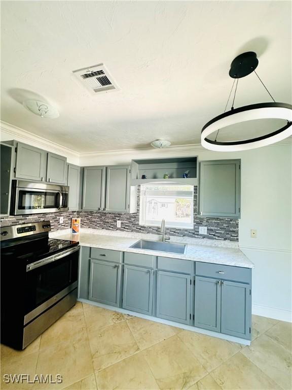 kitchen featuring appliances with stainless steel finishes, pendant lighting, tasteful backsplash, sink, and crown molding