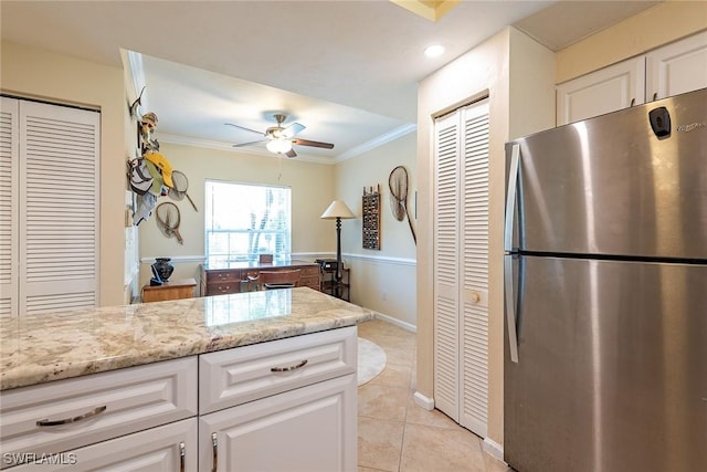 kitchen featuring white cabinetry, light tile patterned floors, ornamental molding, stainless steel fridge, and light stone countertops