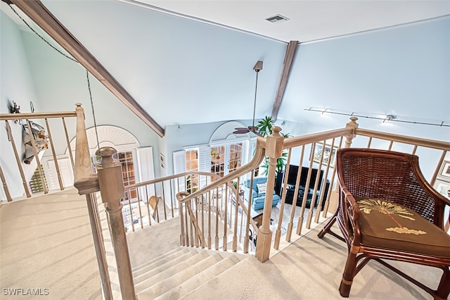 stairway featuring ceiling fan, lofted ceiling with beams, and carpet