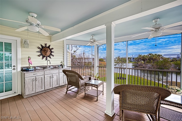 sunroom featuring sink, ceiling fan, and a water view