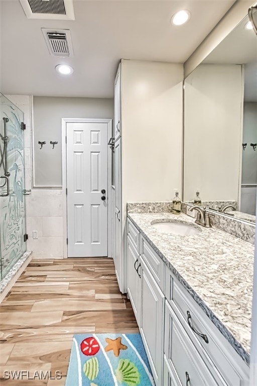 bathroom featuring vanity, wood-type flooring, and a shower with door