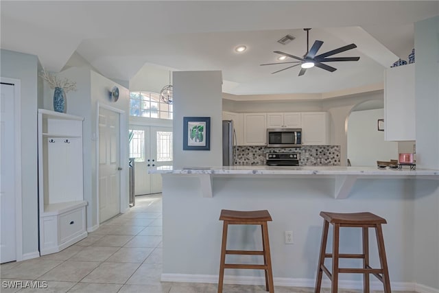 kitchen featuring stainless steel appliances, a breakfast bar, white cabinets, and kitchen peninsula