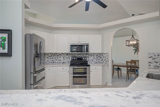 kitchen with backsplash, white cabinets, and appliances with stainless steel finishes