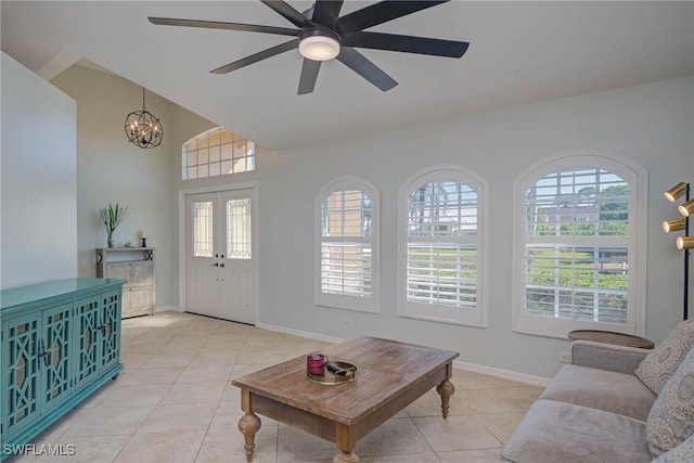 living room with ceiling fan with notable chandelier, light tile patterned floors, and lofted ceiling