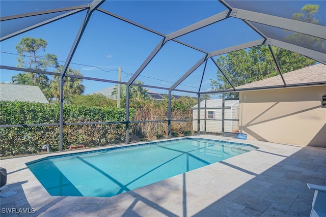 view of pool with a lanai, a patio area, and a storage unit