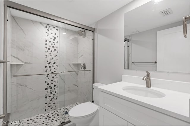 bathroom featuring vanity, toilet, and a shower with door