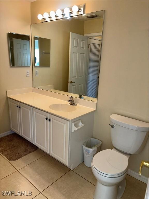 bathroom with toilet, tile patterned floors, baseboards, and vanity