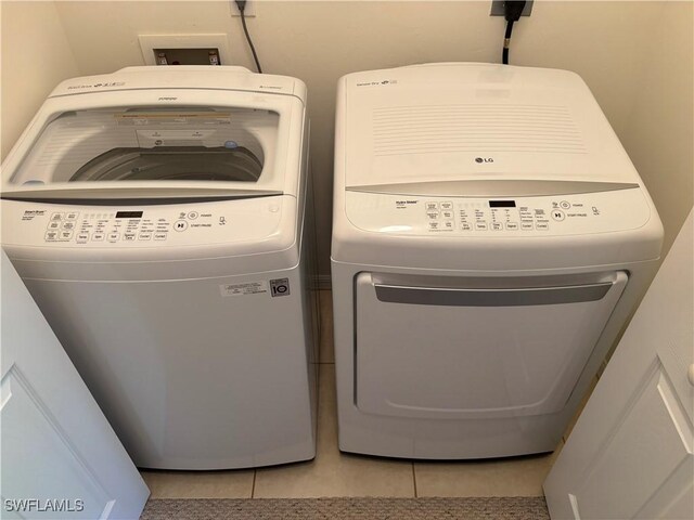 clothes washing area with washing machine and dryer and light tile patterned flooring