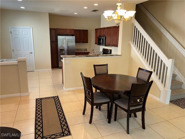 dining room with sink, light tile patterned floors, and a notable chandelier