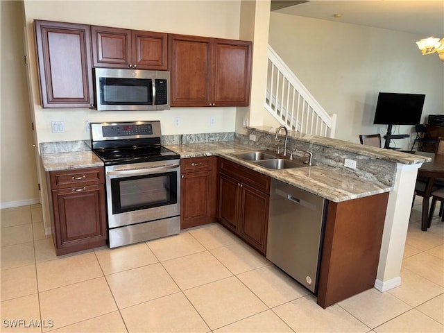 kitchen with sink, light tile patterned floors, light stone counters, kitchen peninsula, and stainless steel appliances