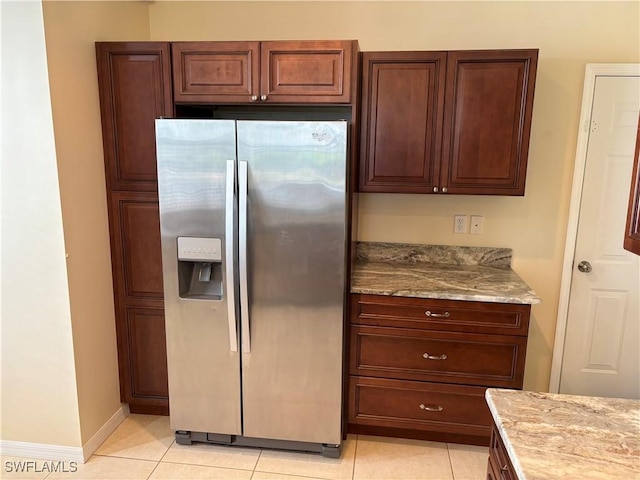 kitchen featuring light stone counters, light tile patterned floors, and stainless steel refrigerator with ice dispenser