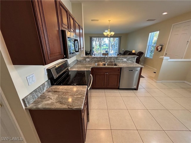 kitchen with light tile patterned flooring, appliances with stainless steel finishes, sink, hanging light fixtures, and light stone counters