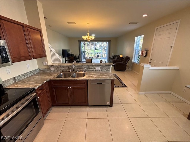 kitchen with light tile patterned flooring, appliances with stainless steel finishes, pendant lighting, sink, and kitchen peninsula