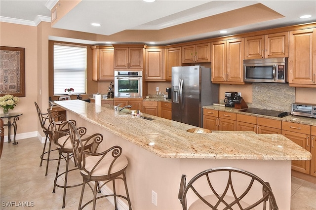 kitchen featuring appliances with stainless steel finishes, a breakfast bar, sink, crown molding, and light stone countertops