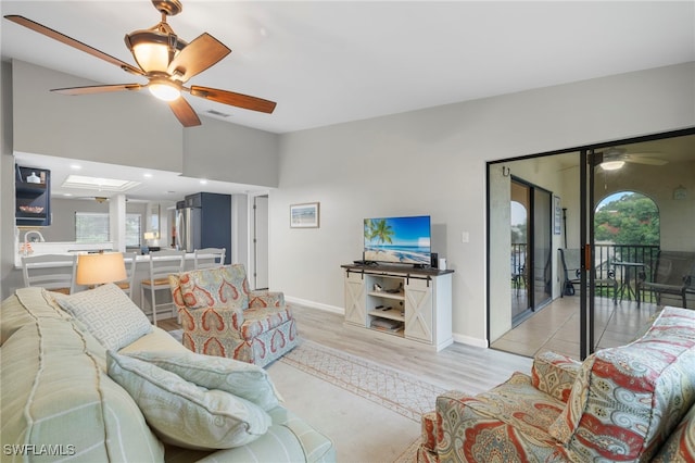 living room with lofted ceiling, ceiling fan, and light wood-type flooring