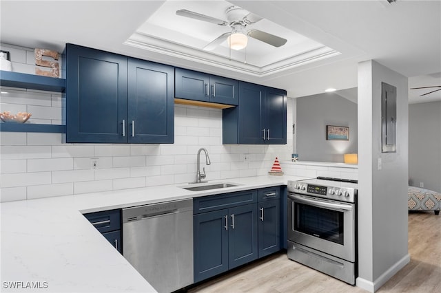 kitchen featuring sink, tasteful backsplash, a raised ceiling, stainless steel appliances, and light stone countertops