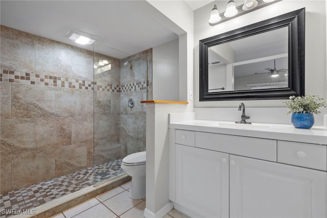 bathroom featuring vanity, a tile shower, tile patterned floors, and toilet