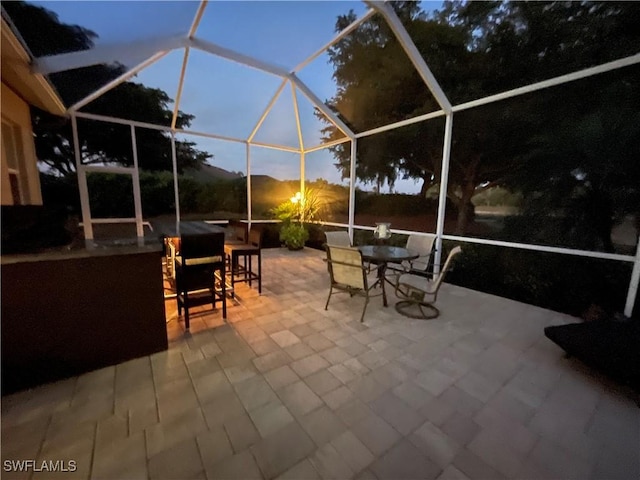 patio terrace at dusk featuring a lanai