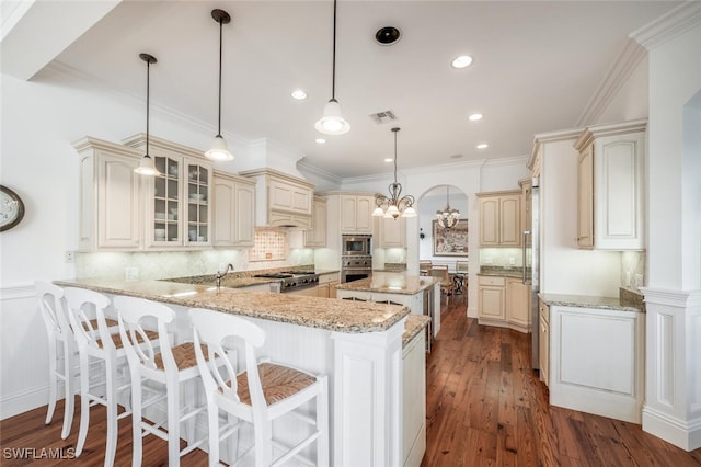 kitchen with stainless steel appliances, pendant lighting, cream cabinetry, and kitchen peninsula