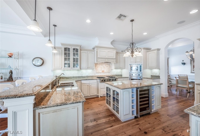 kitchen with hanging light fixtures, sink, stainless steel appliances, and beverage cooler