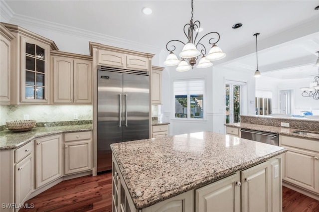 kitchen with a center island, ornamental molding, appliances with stainless steel finishes, a notable chandelier, and pendant lighting