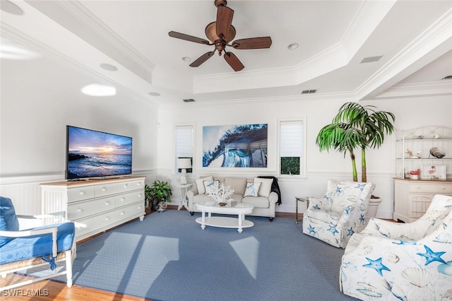 living room featuring a raised ceiling, ornamental molding, and ceiling fan