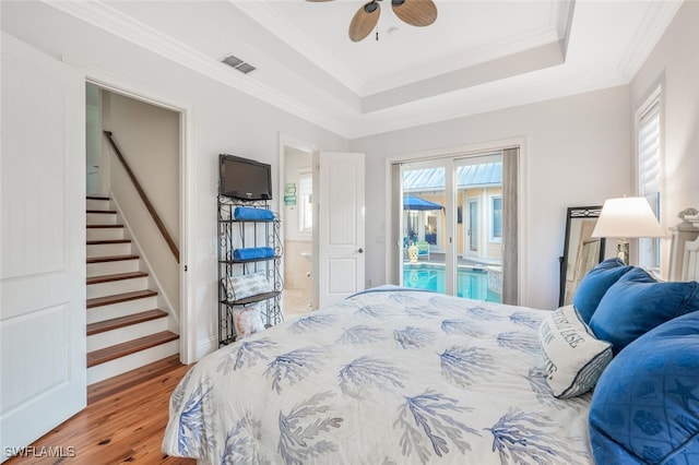 bedroom with wood-type flooring, access to outside, ceiling fan, a raised ceiling, and crown molding