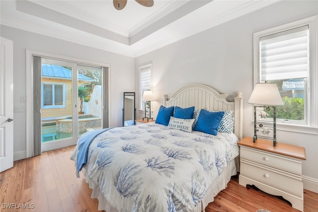 bedroom with hardwood / wood-style floors, ornamental molding, access to outside, ceiling fan, and a raised ceiling