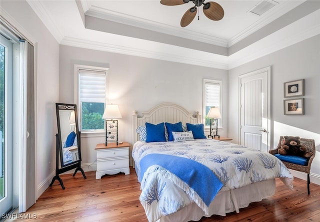 bedroom featuring hardwood / wood-style floors, ornamental molding, a raised ceiling, and ceiling fan