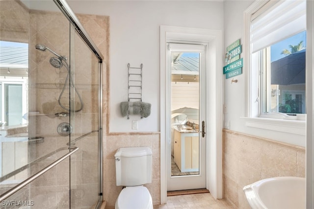 bathroom featuring toilet, tile walls, and shower with separate bathtub