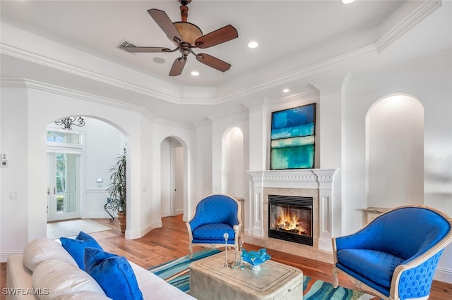 living room featuring crown molding, a premium fireplace, and light hardwood / wood-style flooring