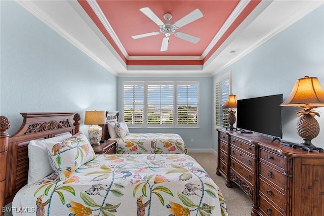 carpeted bedroom with a tray ceiling, crown molding, and ceiling fan