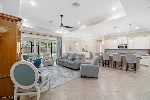 tiled living room with crown molding, ceiling fan, and a tray ceiling