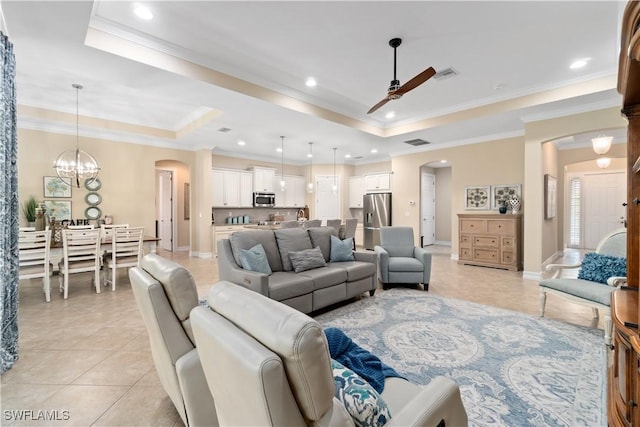 living room with arched walkways, a raised ceiling, visible vents, and ceiling fan with notable chandelier