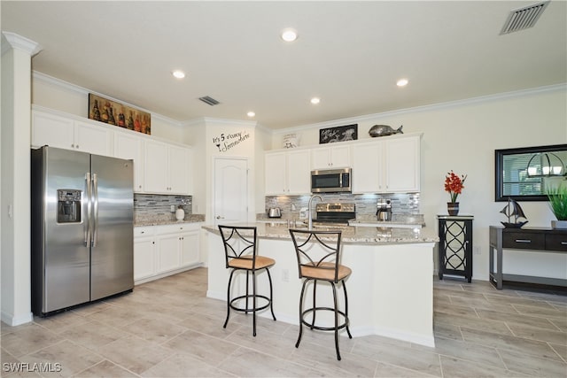 kitchen featuring white cabinetry, a center island with sink, light stone countertops, and appliances with stainless steel finishes