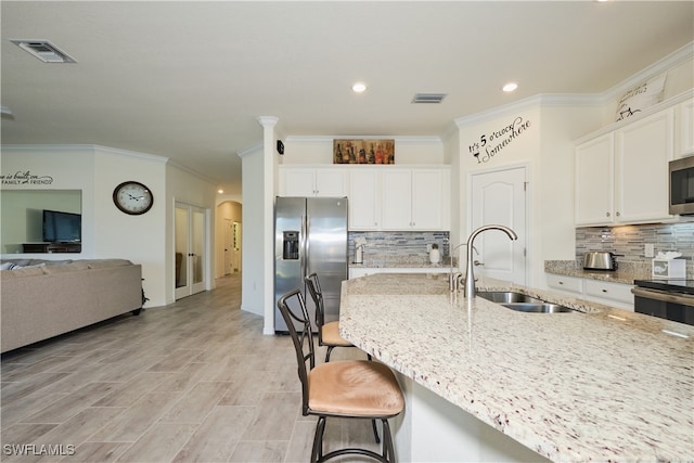 kitchen featuring sink, a kitchen breakfast bar, stainless steel appliances, light stone countertops, and white cabinets