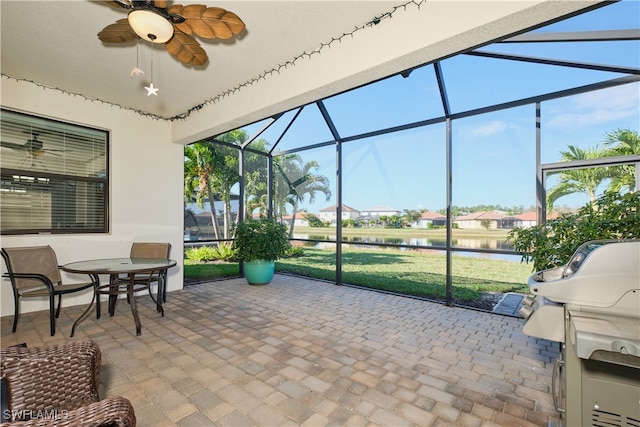 sunroom with a healthy amount of sunlight, ceiling fan, and a water view